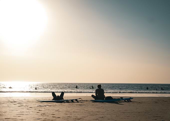 Surfers Relaxing on Beach at Sunset