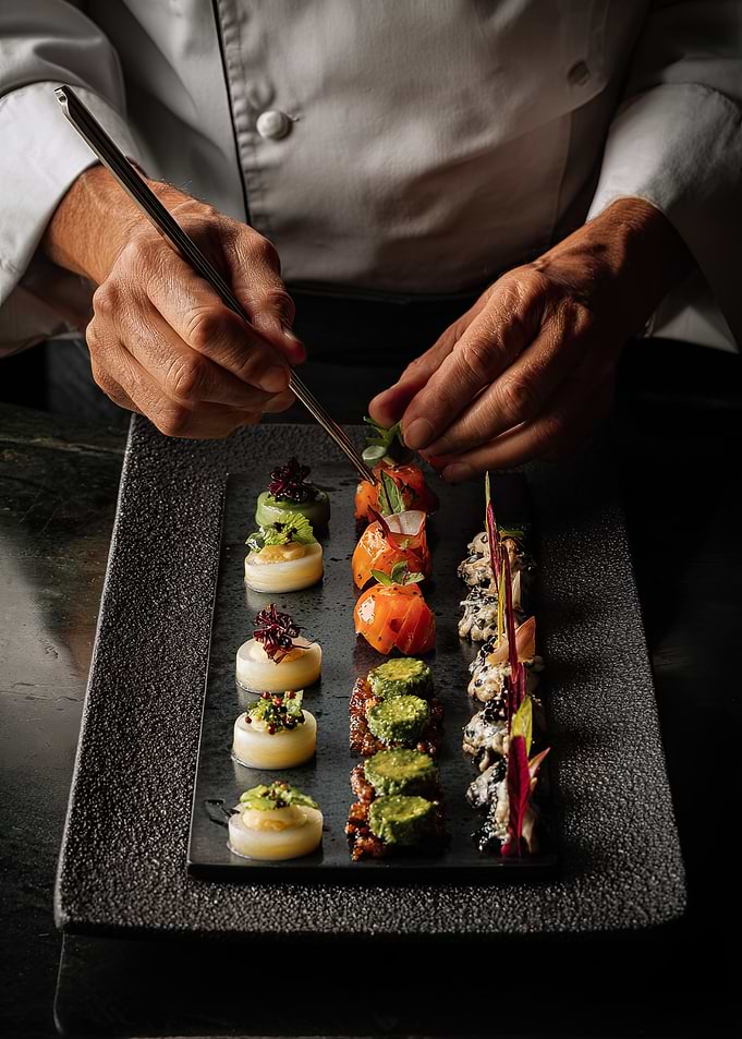 Chef plating gourmet appetizers with tweezers