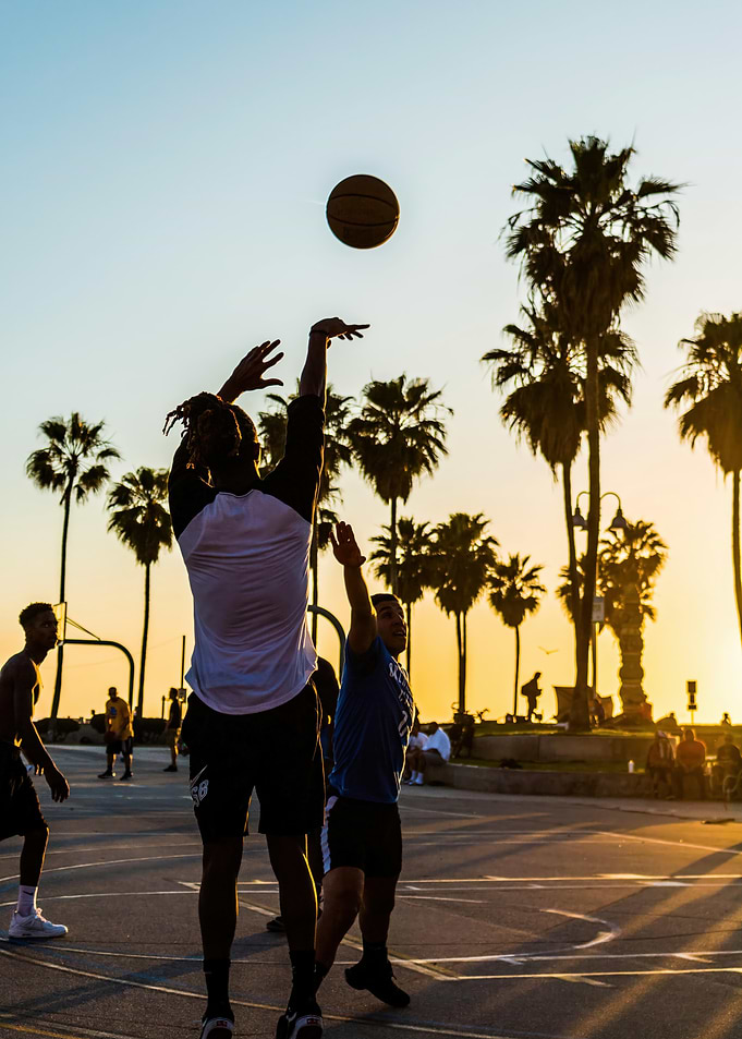 Basketball game at sunset with palm trees