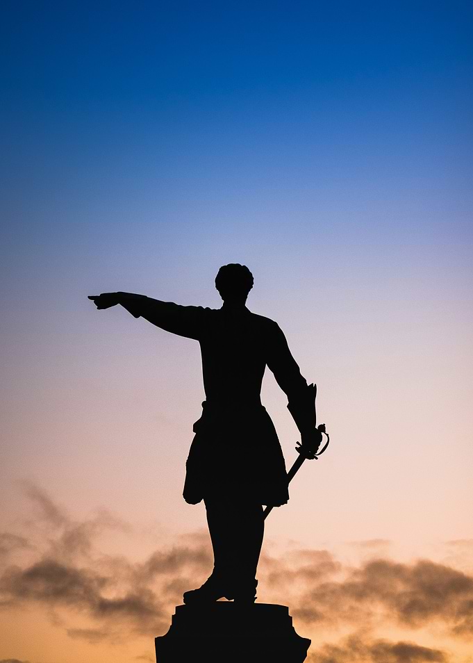 Silhouette of Statue Against Colorful Sky