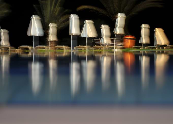 Night Poolside with Umbrellas and Reflections