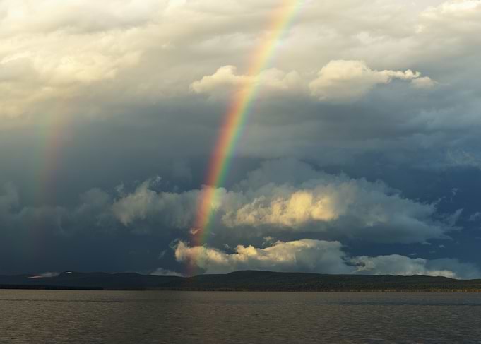 Rainbow over Lake and Cloudy Sky