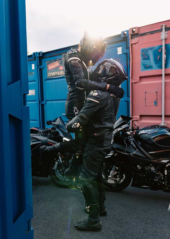Motorcycle riders embracing near shipping containers