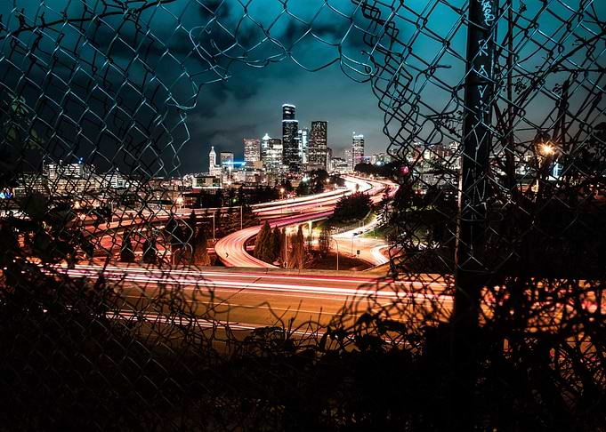 seattle skyline through broken fence at night