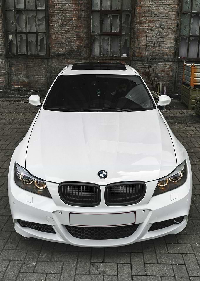 White BMW parked near brick building