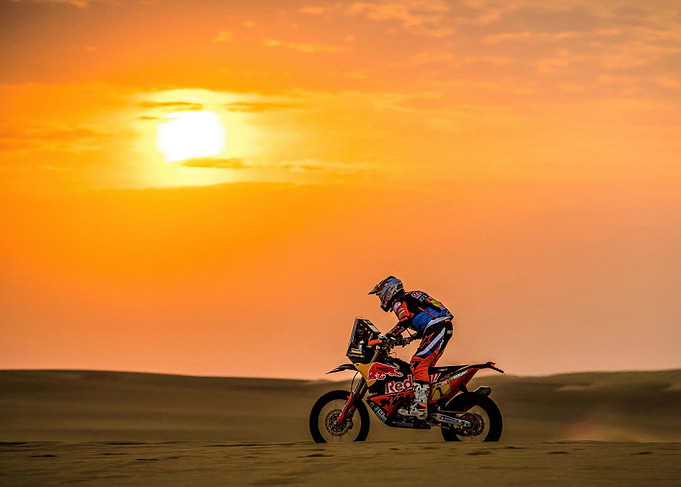 Motorcycle racing in the desert sunset