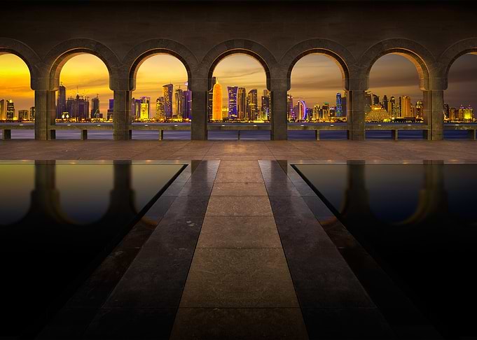 doha skyline through arches at sunset