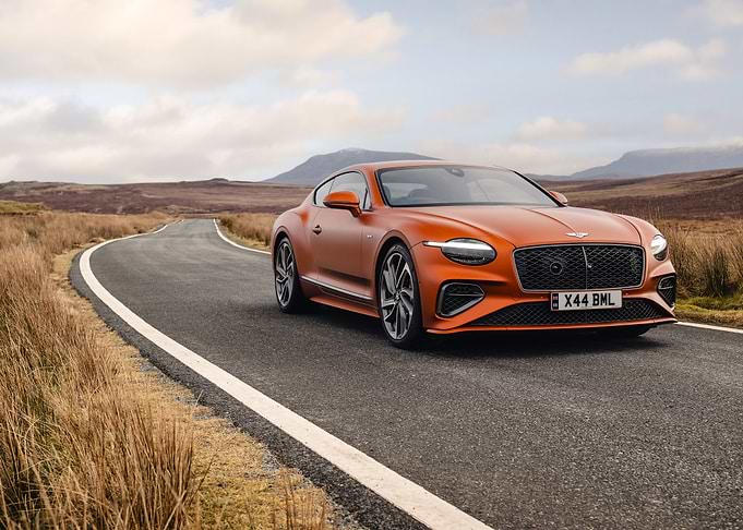 orange bentley on a winding road