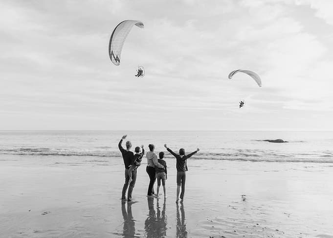 Family watching paragliders on the beach