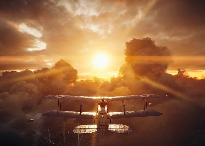 Biplane flying through clouds at sunset