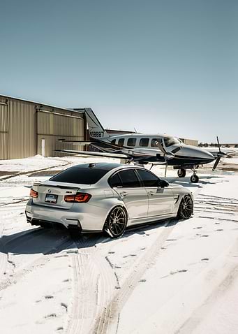 Silver BMW and Airplane on Snowy Ground
