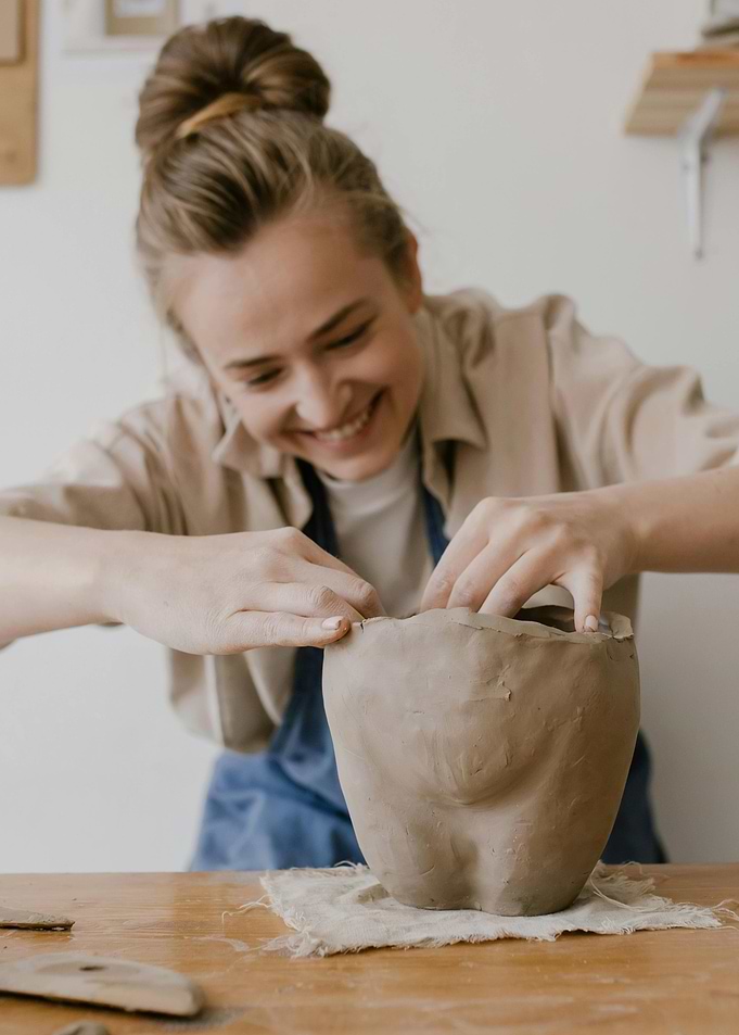 Woman shaping clay pot in studio