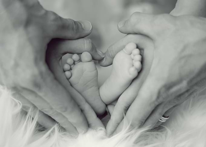 Baby feet in heart-shaped hands
