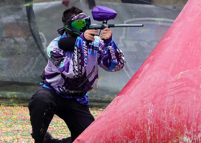 Paintball Player Aiming Behind Red Barrier