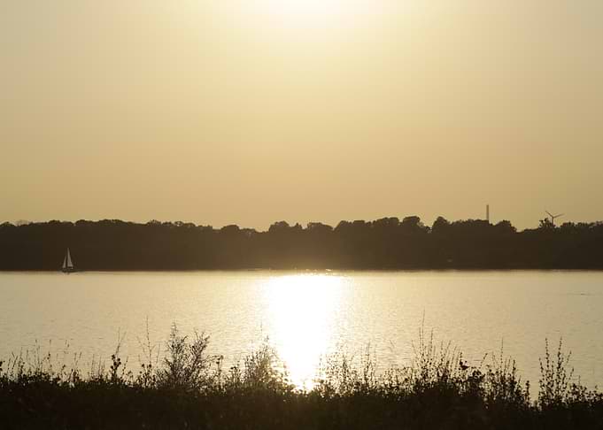 Golden Sunset Over Water with Sailboat