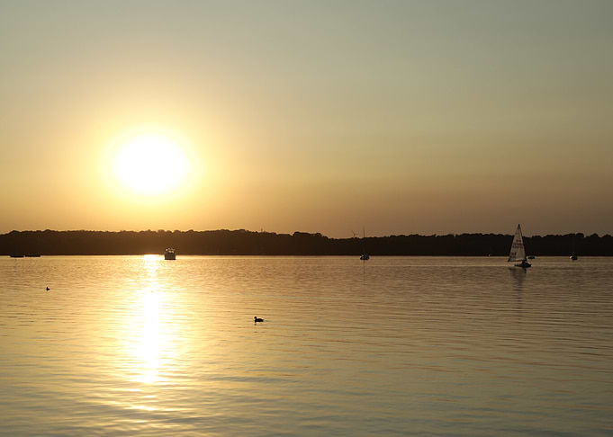 Sunset over lake with sailboats