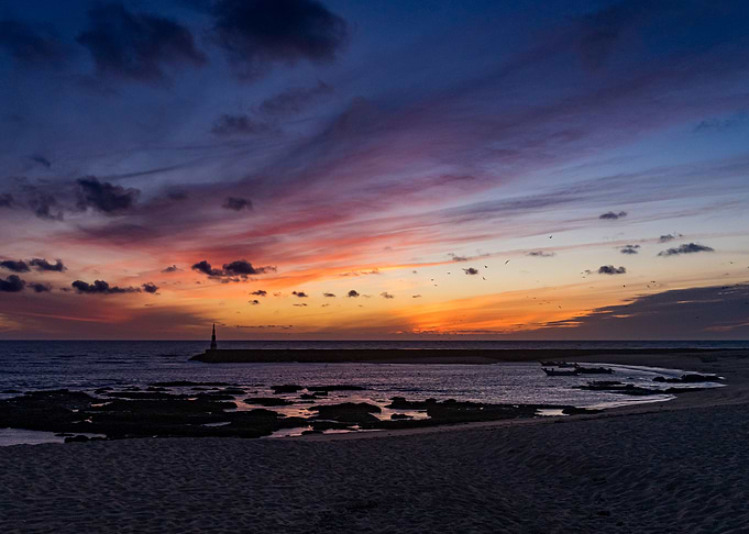 Sunset over the ocean with lighthouse