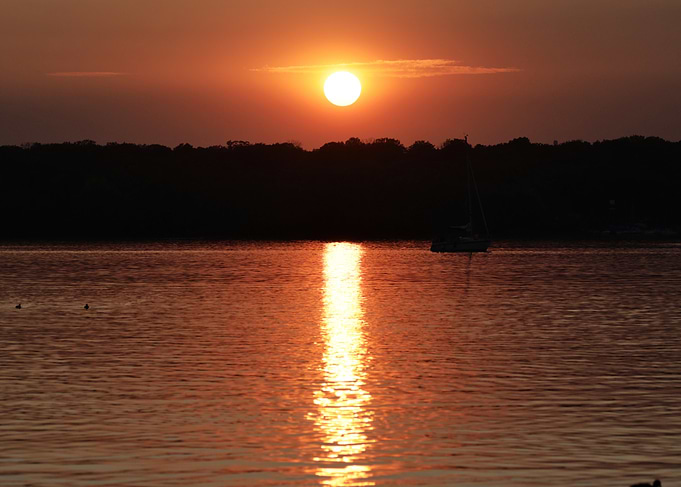 Sunset over water with boat silhouette