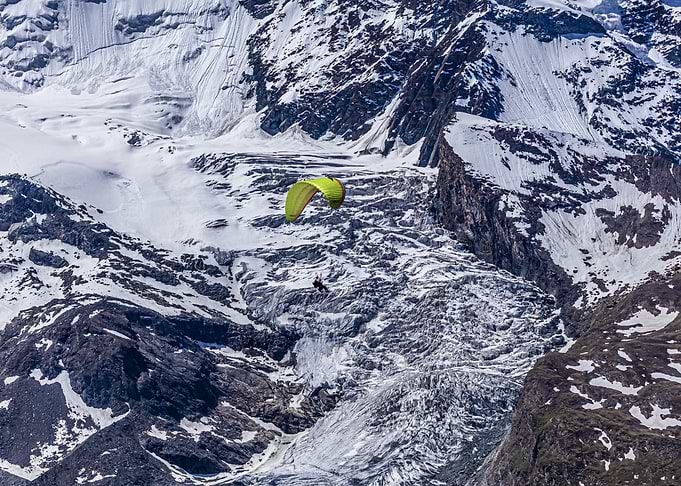 Paragliding over snowy mountain landscape