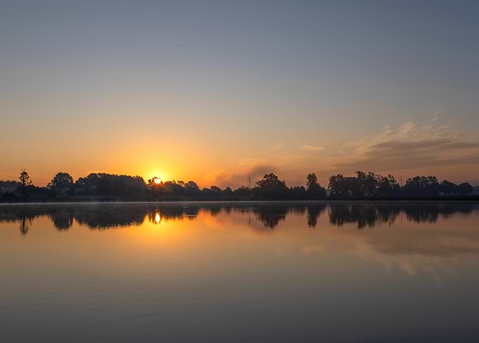 Sunrise over calm water reflection