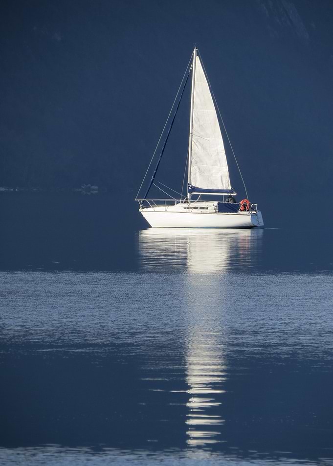Sailboat on calm water, mountain backdrop