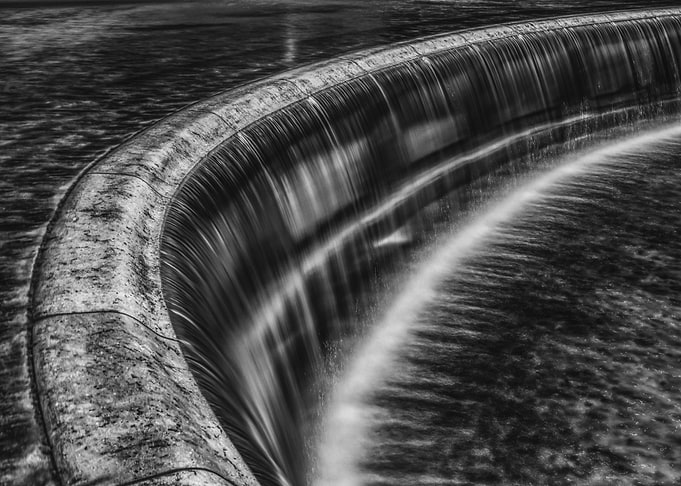 Monochrome Waterfall Over Curved Dam
