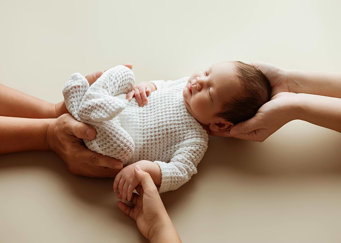 Newborn baby sleeping in parents' hands