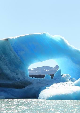 Blue Iceberg with Archway and Mountains