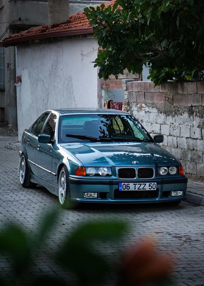 Teal BMW E36 on Cobblestone Street