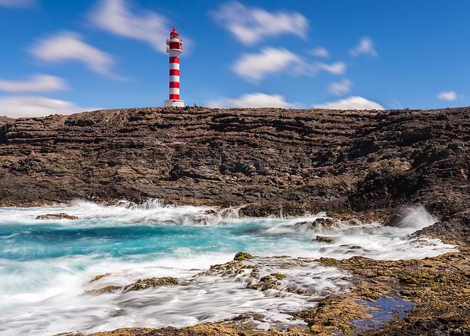 Red and White Lighthouse on Rocky Coast