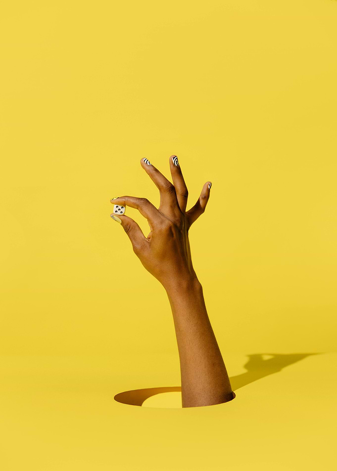 Hand Holding Dice on Yellow Background