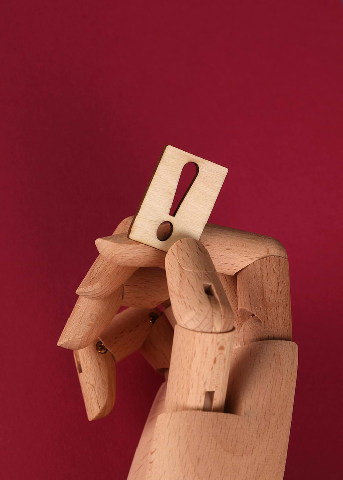 Wooden hand holding exclamation mark