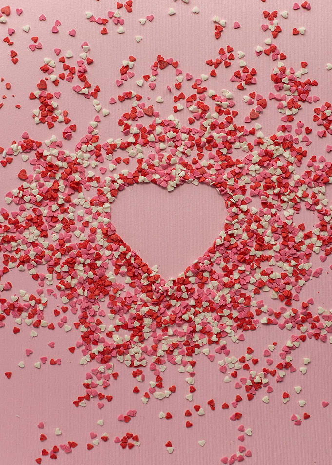 Heart-shaped sprinkles on pink background