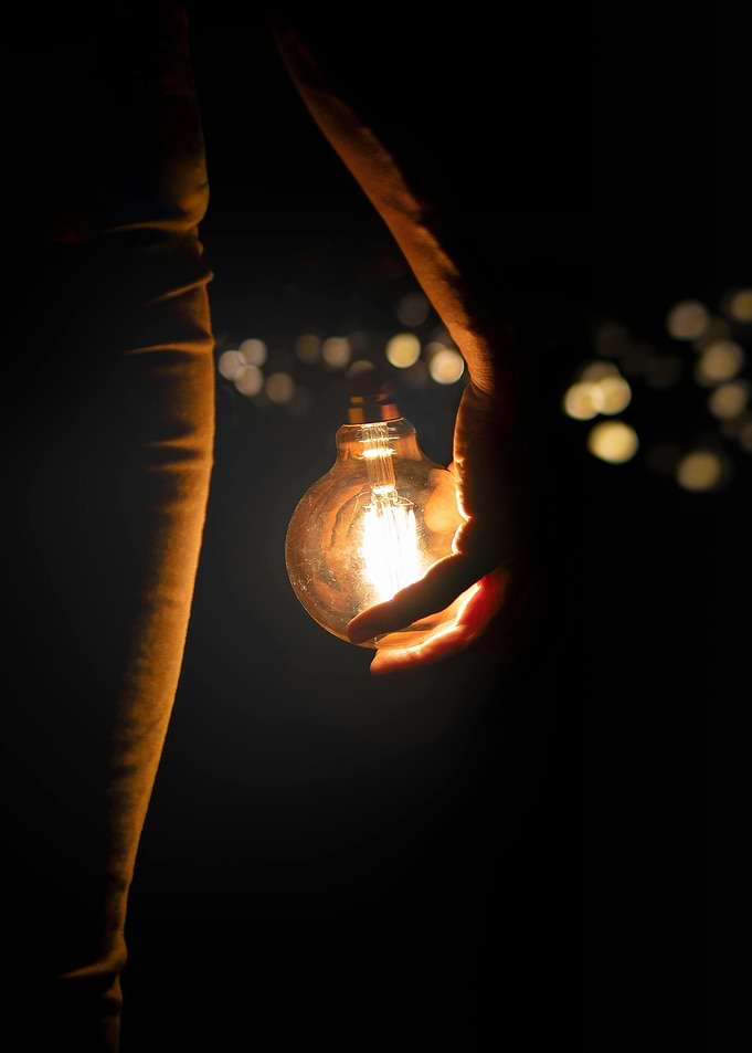 Hand holding a glowing light bulb
