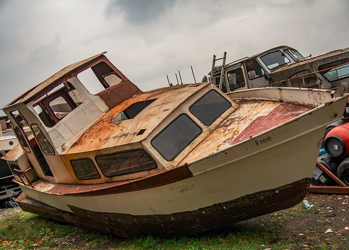 Abandoned Rusty Boat on Grassy Ground