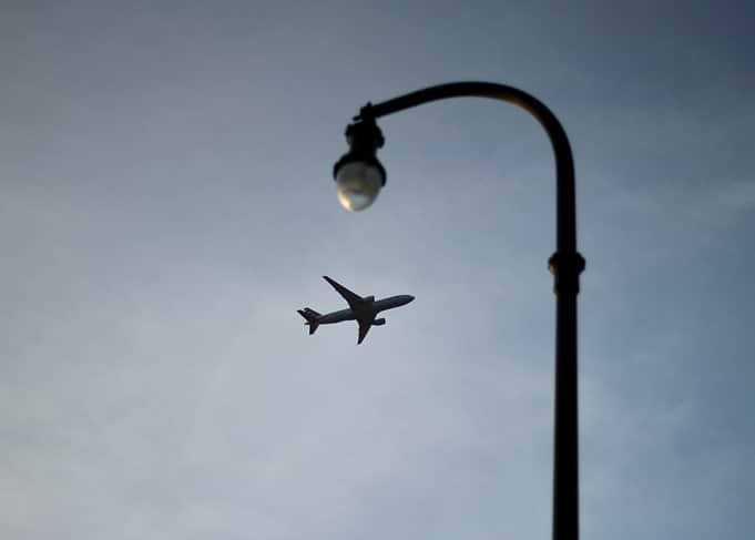 Airplane flying near a street lamp