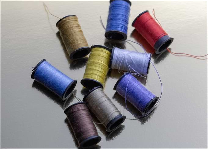 Colorful Thread Spools on Reflective Surface