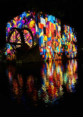 Illuminated Building with Water Wheel Reflection