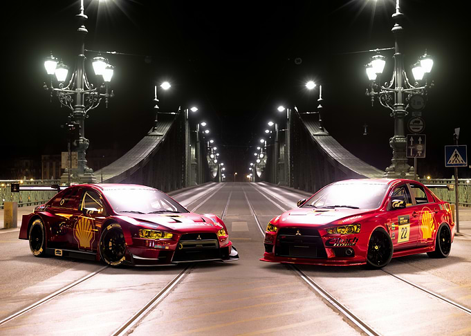 Two Red Mitsubishi Race Cars on Bridge