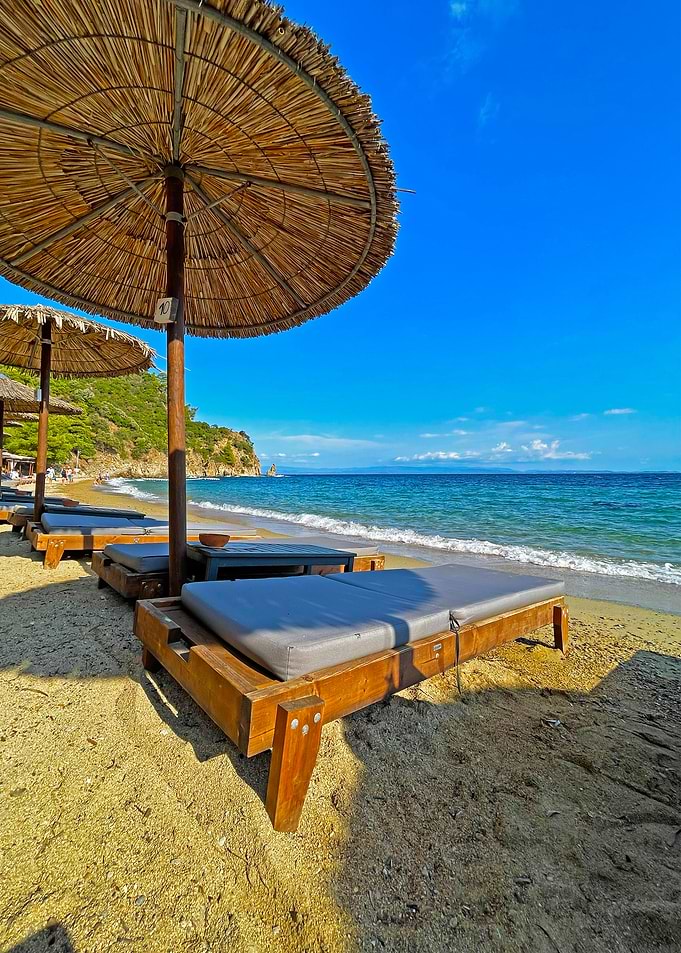 Beach loungers with umbrellas on sandy beach