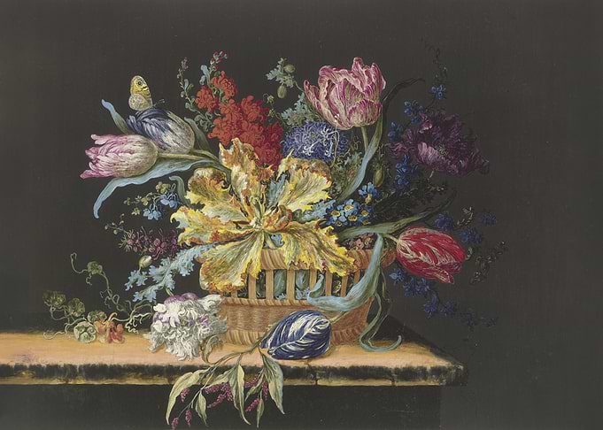 Flower basket with tulips, stocks, delphiniums and other flowers on a table