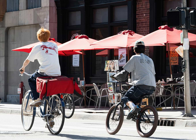 Two Cyclists on a City Street Cortis