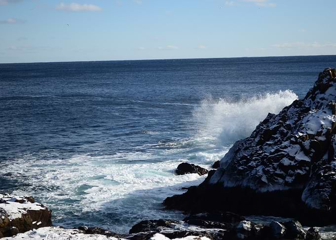 Ocean waves crashing on snowy rocks