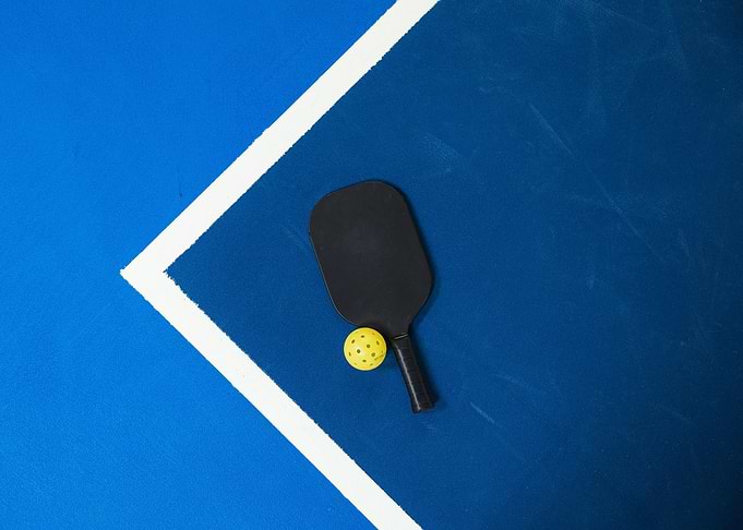 Pickleball paddle and ball on court