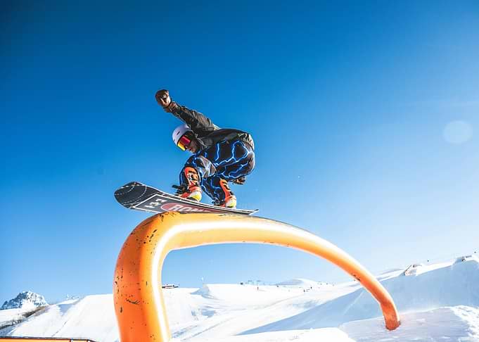 Snowboarder Jumping Over Orange Rail