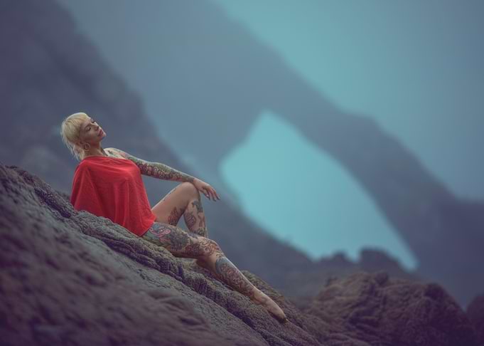 Tattooed Woman in Red on Rocks