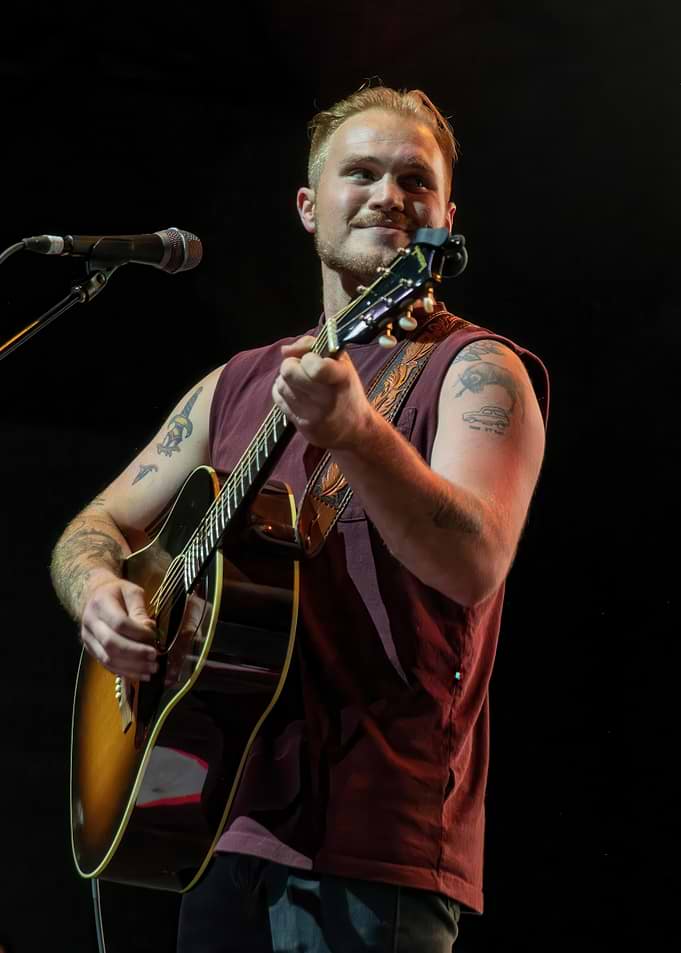 Musician playing acoustic guitar on stage