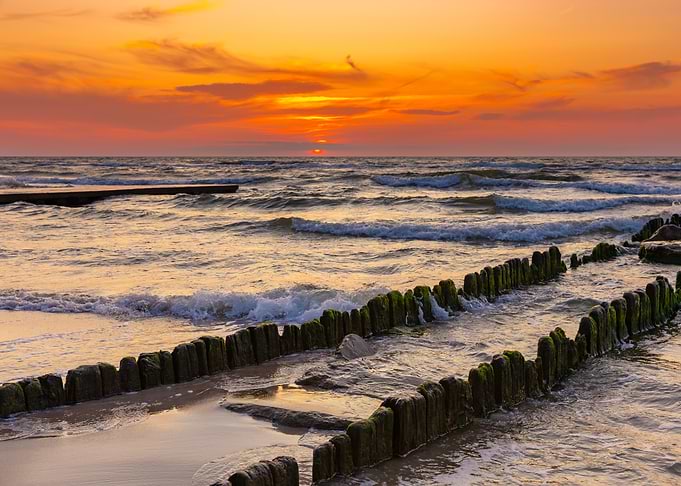 Sunset over the sea with wooden breakwaters, Poland