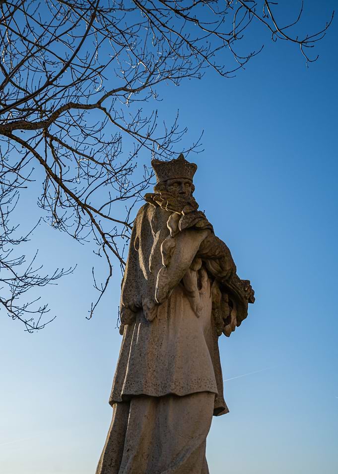 Stone Statue with Crown Against Blue Sky
