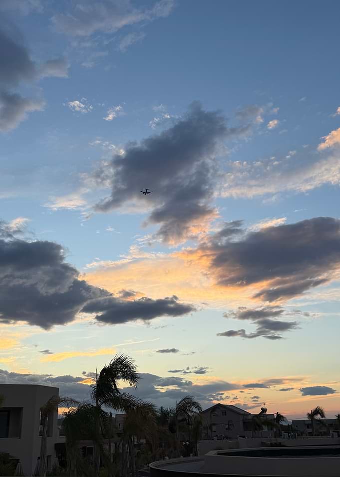 Airplane flying in a cloudy sunset sky